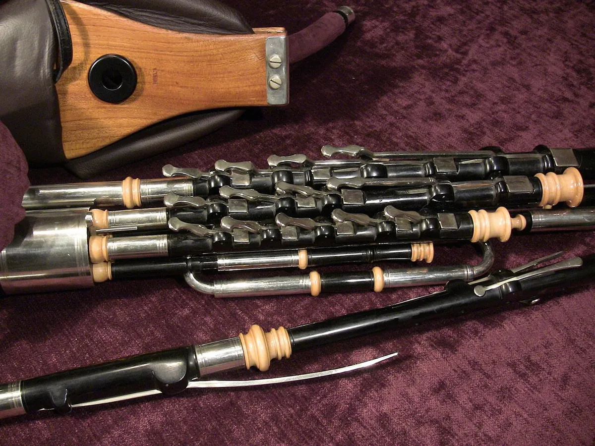 Un juego de uilleann pipes dispuesto mostrando la bolsa, los fuelles y el chanter con sus llaves